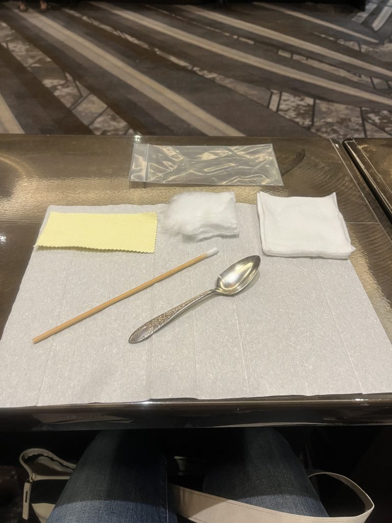 Practicing cleaning silver spoons during precious metals conservation workshop.