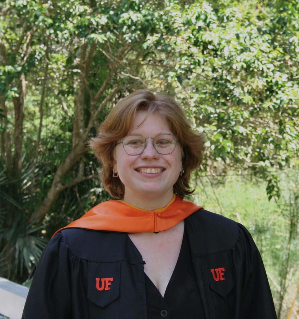 woman in black graduation robes and orange sash