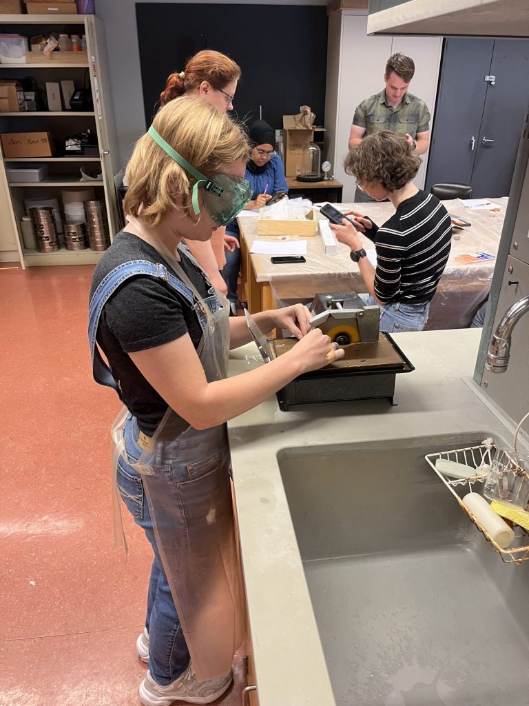 Gloria Church using a saw to cut ceramic samples into a thin section slide