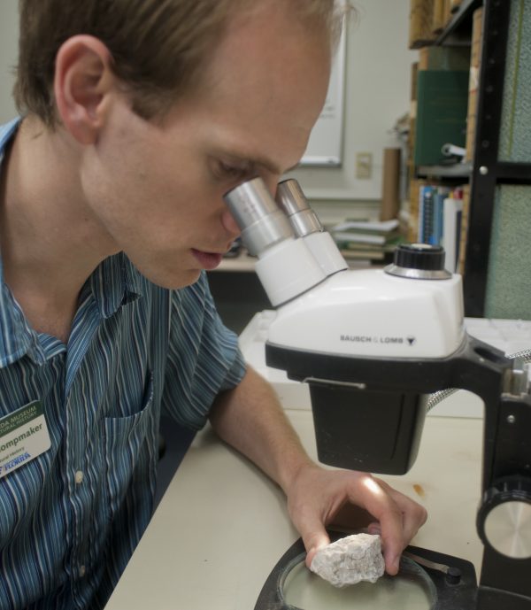 Klompmaker examining fossil under microscope