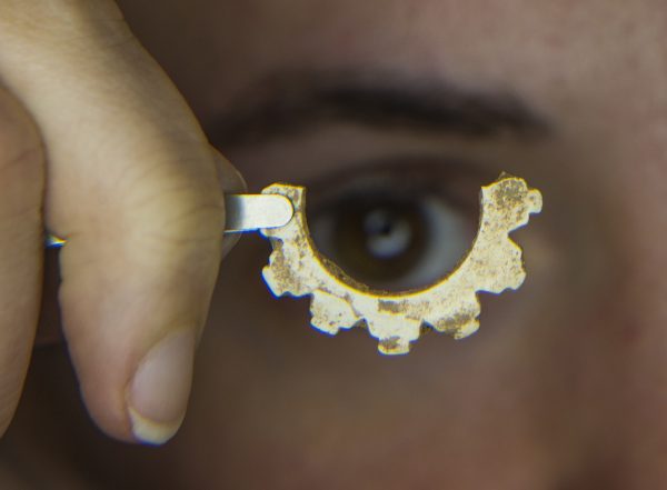 Museum doctoral examines a piece of marine shell made into an ornament.