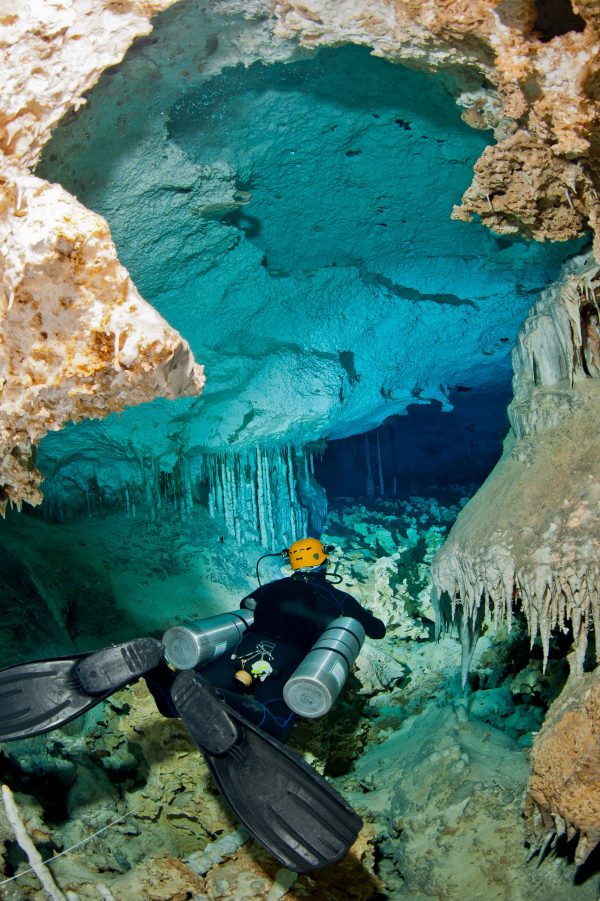 diver swimming through a narrow passageway