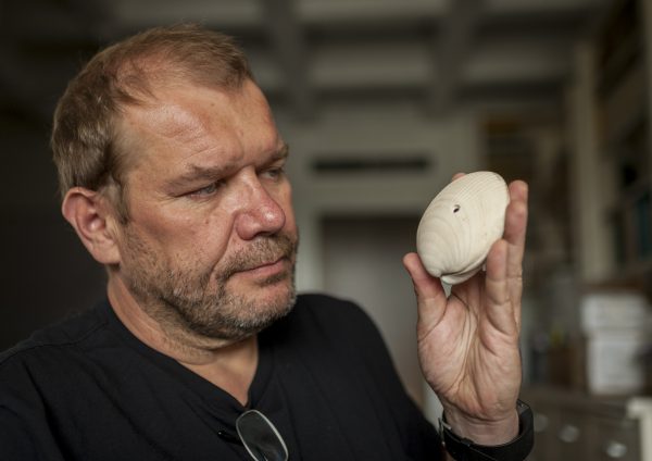 Researcher Michal Kowalewski holds a fossil shell bearing the mark from a drilling predator