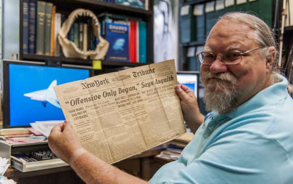 George holding up old newspaper