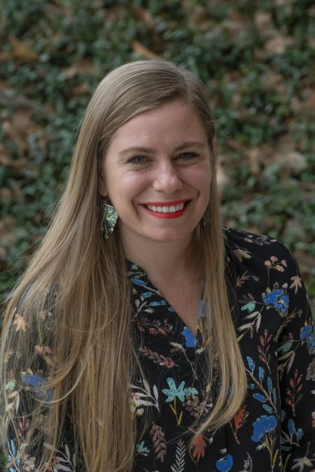 smiling woman against backdrop of greenery