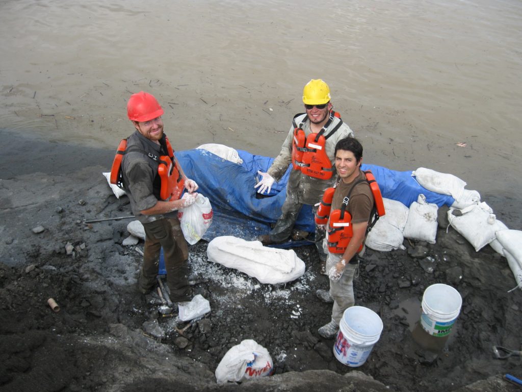 three men in life jackets stand by plaster jacket