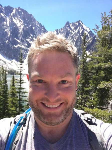 selfie of Richie smiling in front of mountains