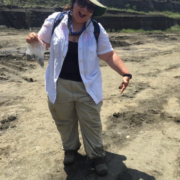 scientist poses with a bag of fossils