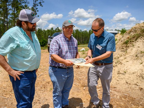 three researchers stand at the montbrook dig site