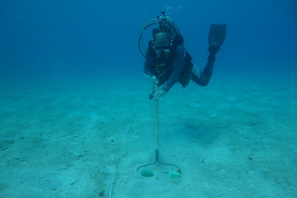 person in scubasuit raking seafloor