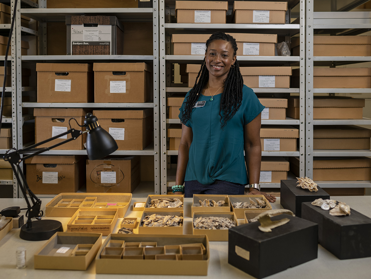 Cannarozzi stands in front of shelves of specimens in boxes, while in front of her many open specimen boxes lay on a table