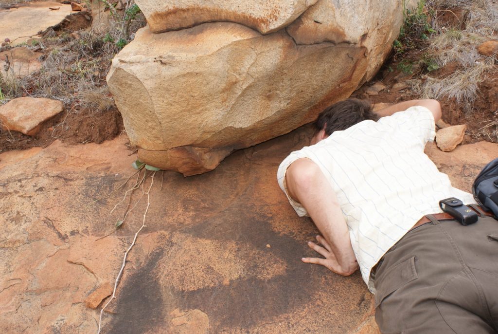 A scientist peers under a rock