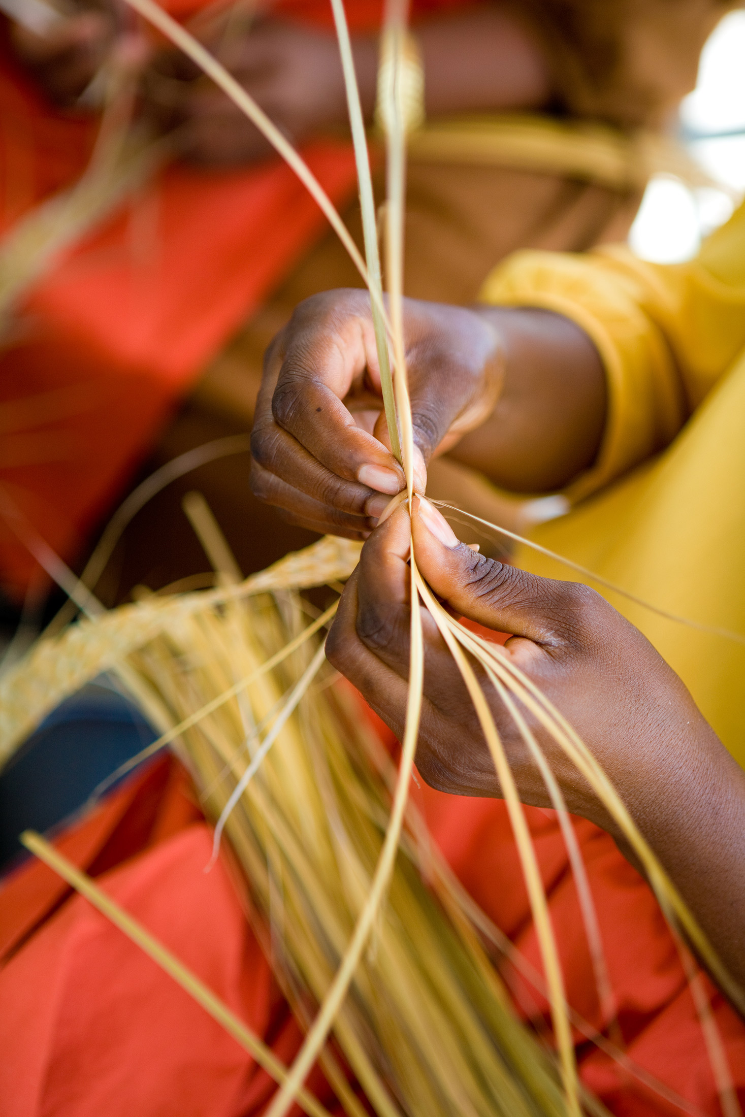 Person shown weaving a basket out dried grass stalks