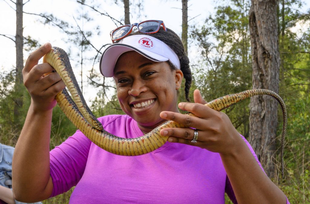 Adania Flemming holds a snake aloft, with a big smile