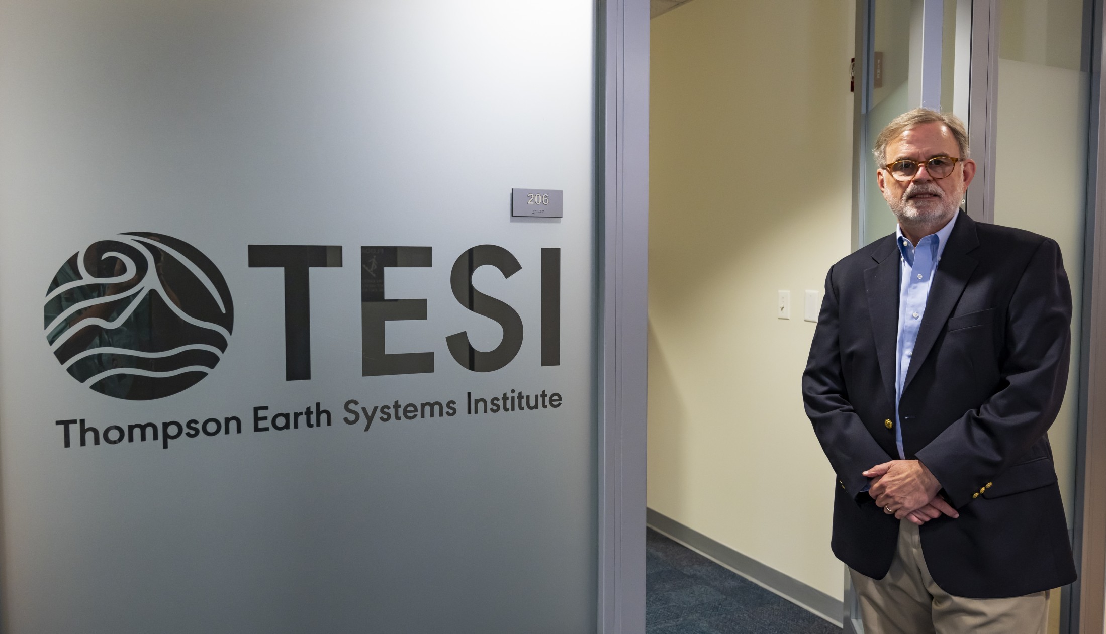 Man standing in front of a doorway, with a logo printed on the glass of the adjacent wall