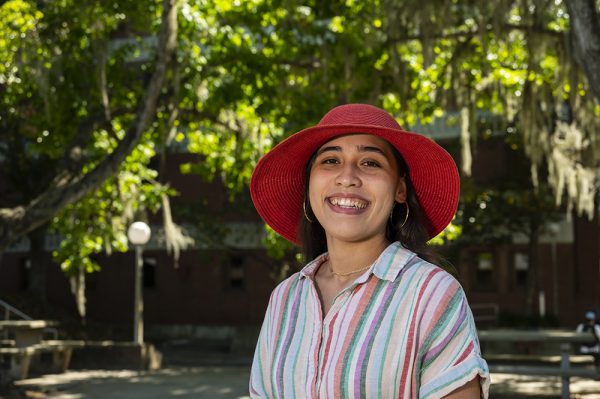 woman in red hat smiling in front of a tree