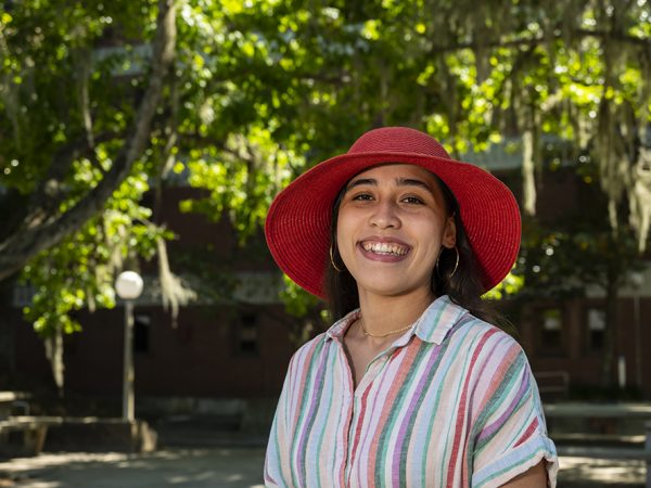 woman in red hat smiling in front of a tree