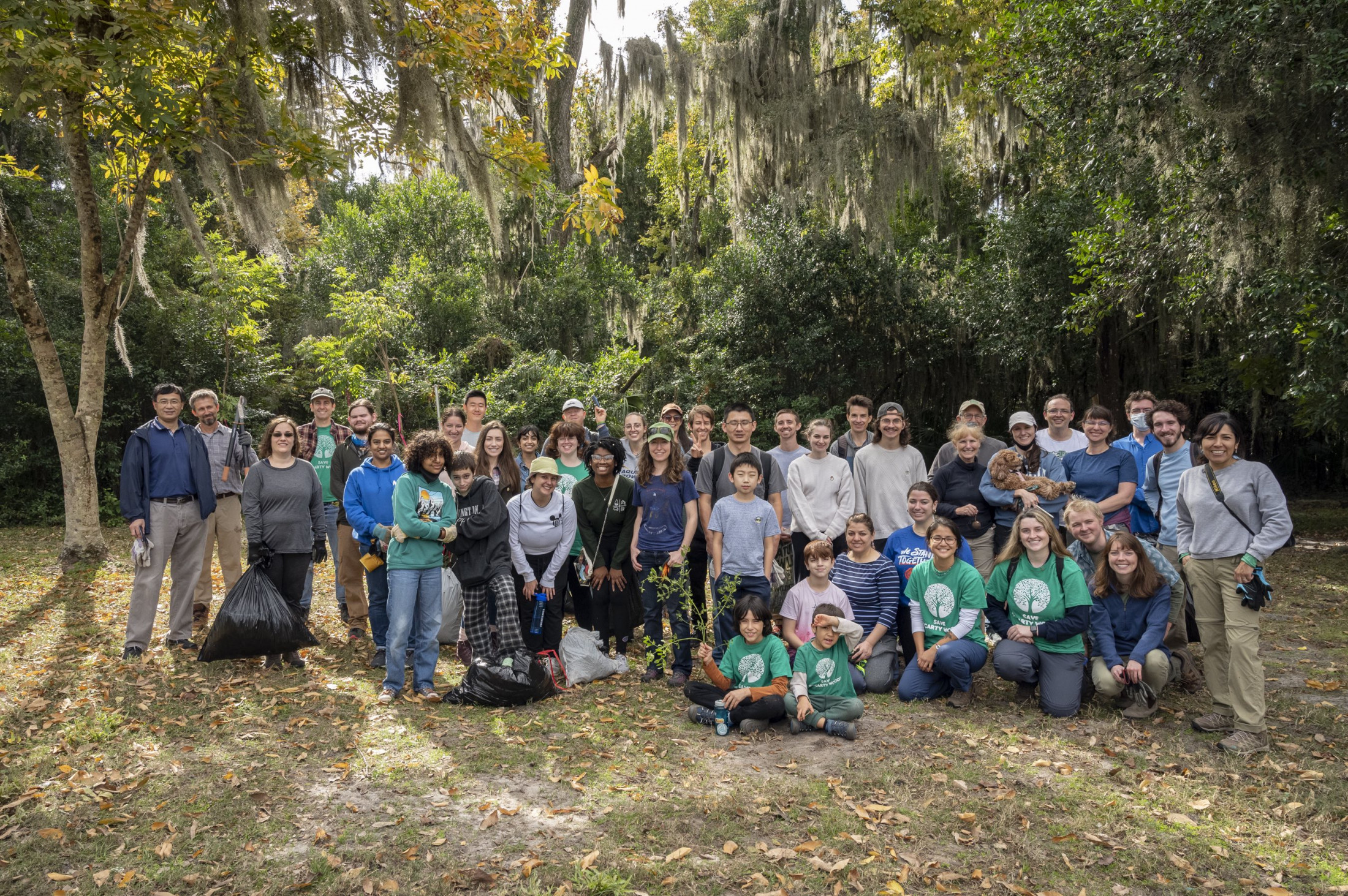 Group of people standing on a lawn clearing in front of a forest 