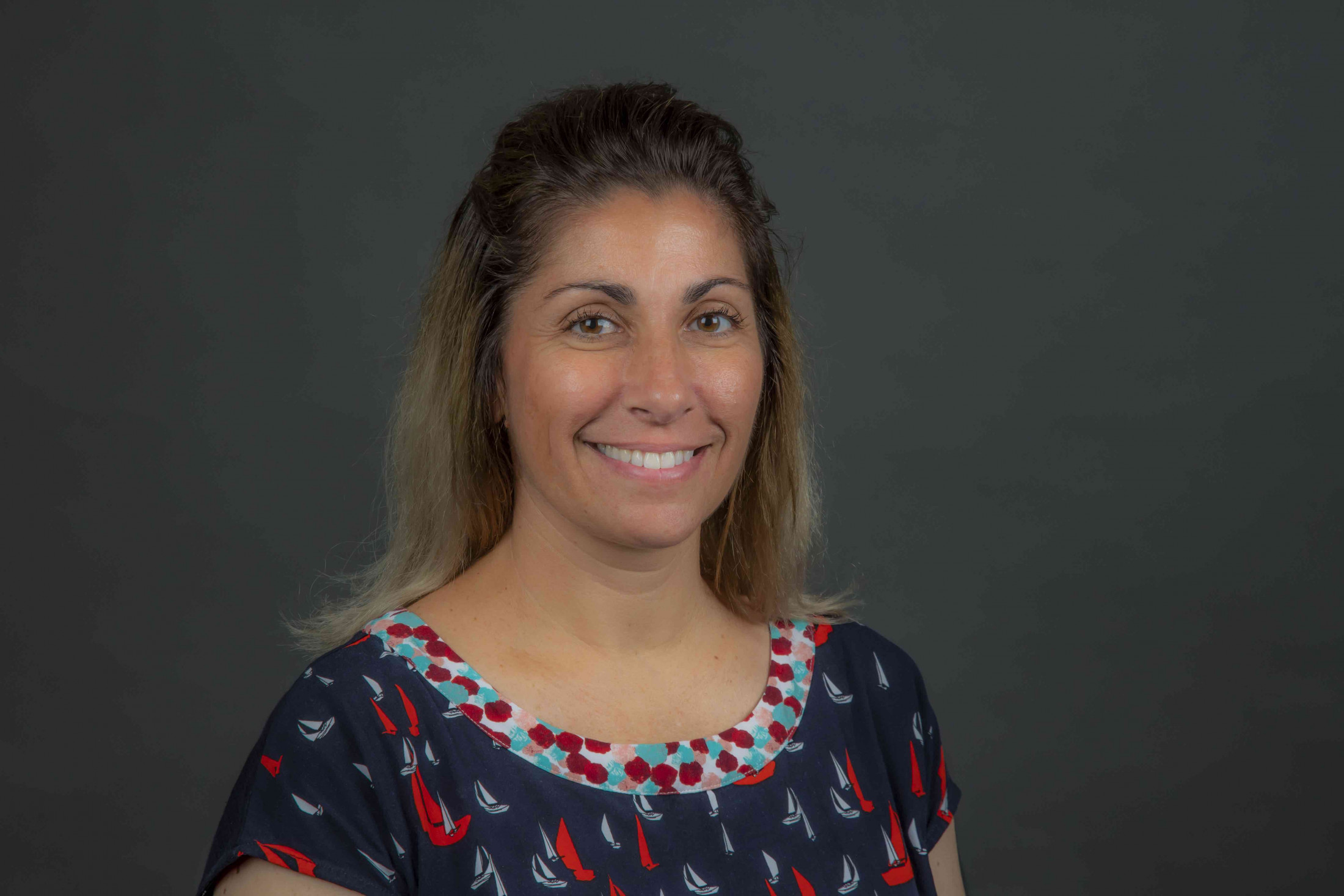 Woman smiles in front of gray background