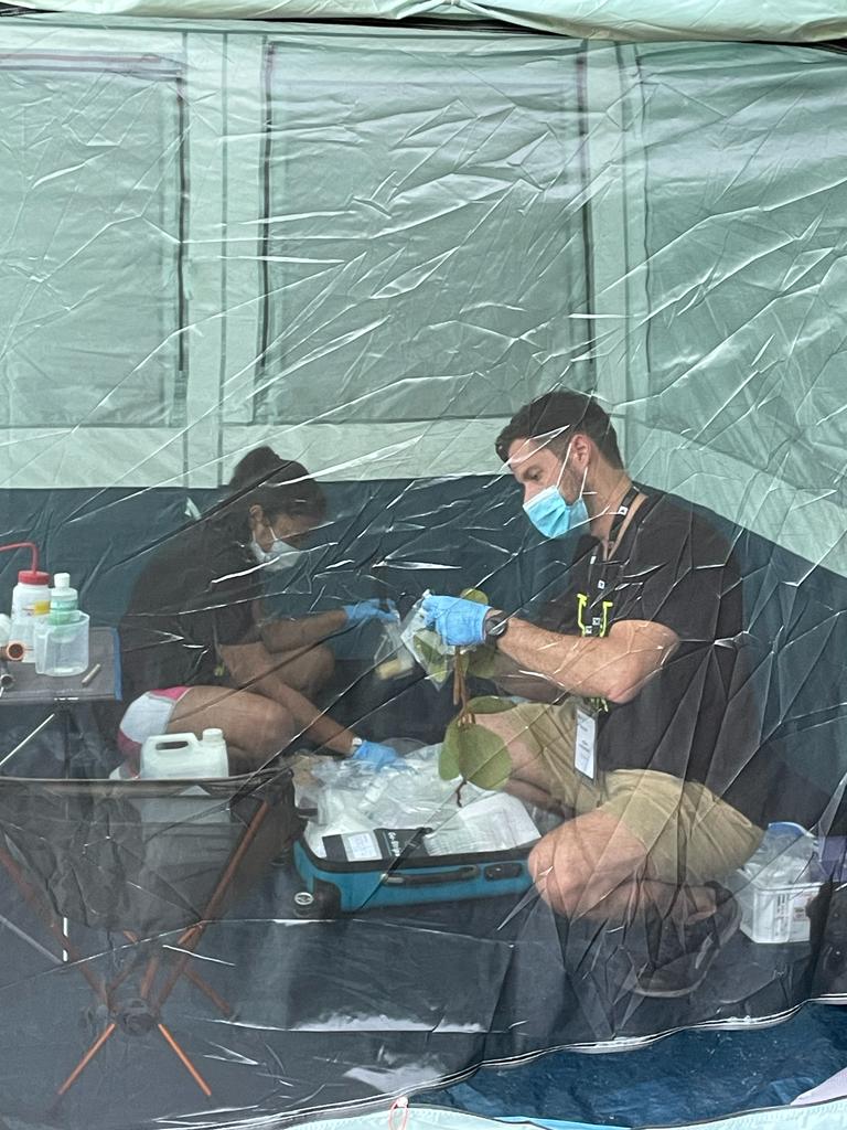 Two people working with lab equipment in a tent