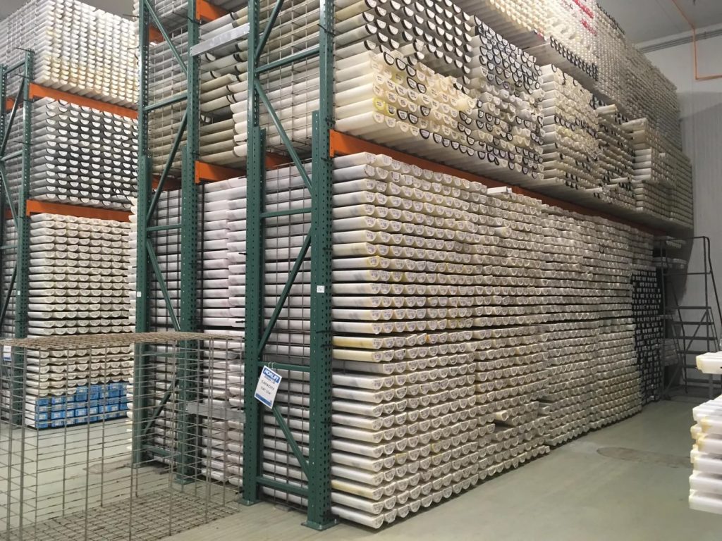 Photograph of sediment cores stored in tubes stored on industrial shelving units.