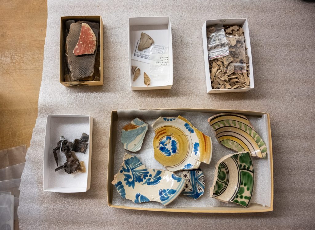 Photograph looking down at four boxes with various broken artifacts.