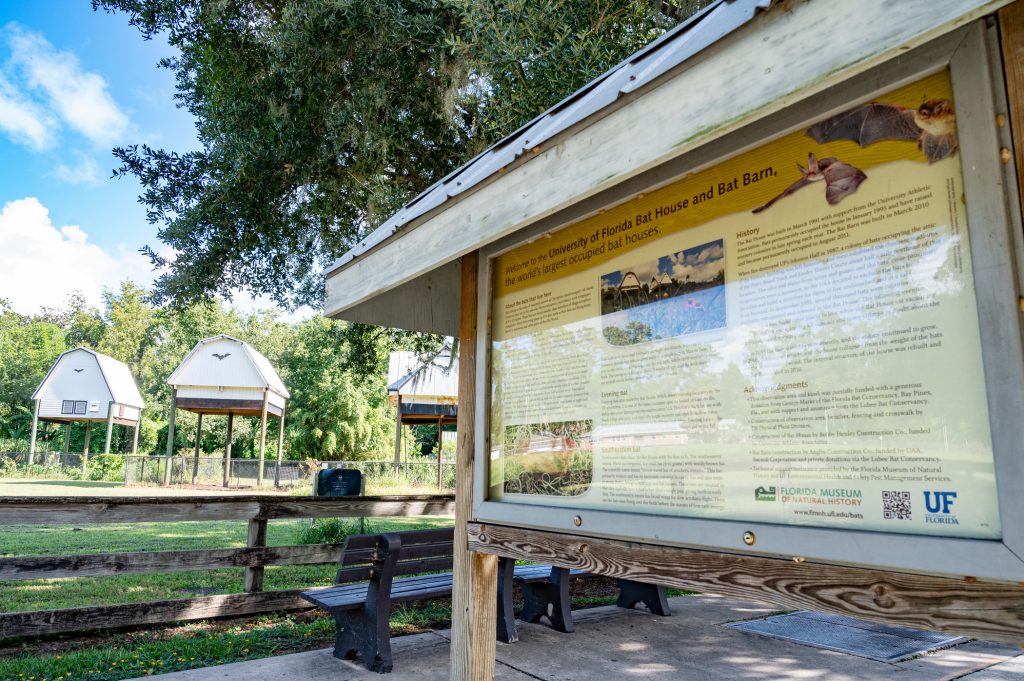information signage about the bats in the ouses is set near several benches with bat houses in the distance