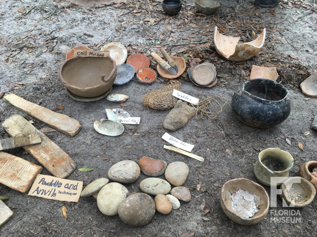 An array of pottery tools with a coil pot in process