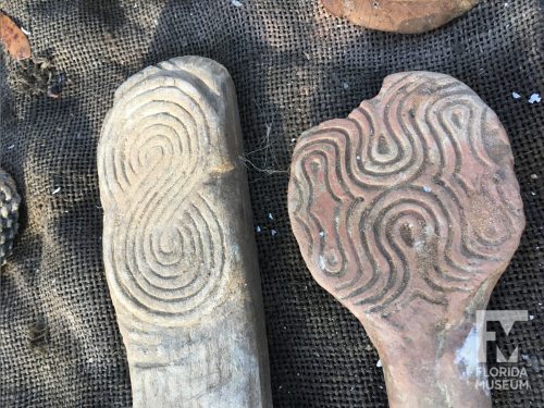 two wooden paddles with curvilinear designs