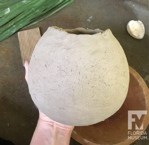 Rounded pot held in hand with rough rim