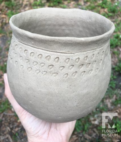 Jar held in hand with punctated decoration