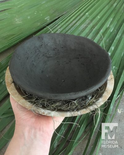 Black pottery bowl sitting in wooden bowl