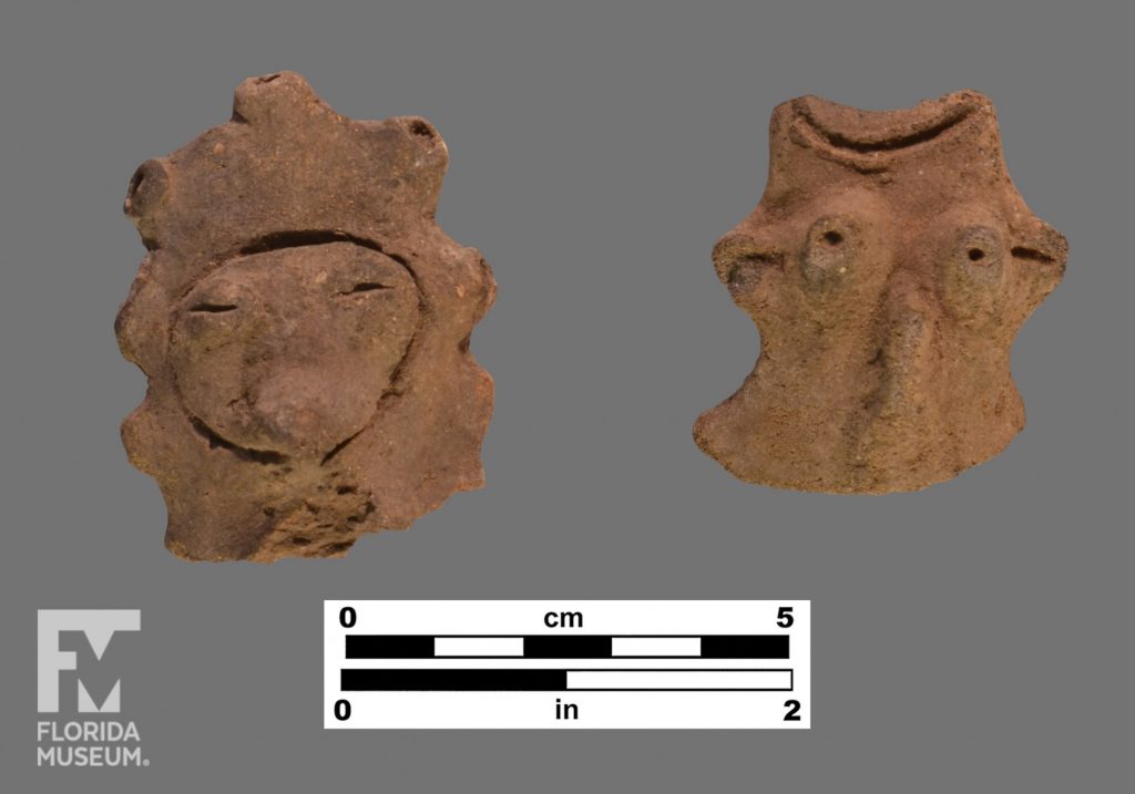 Formal artifact photo of two human effigy adornos with faces and headdresses