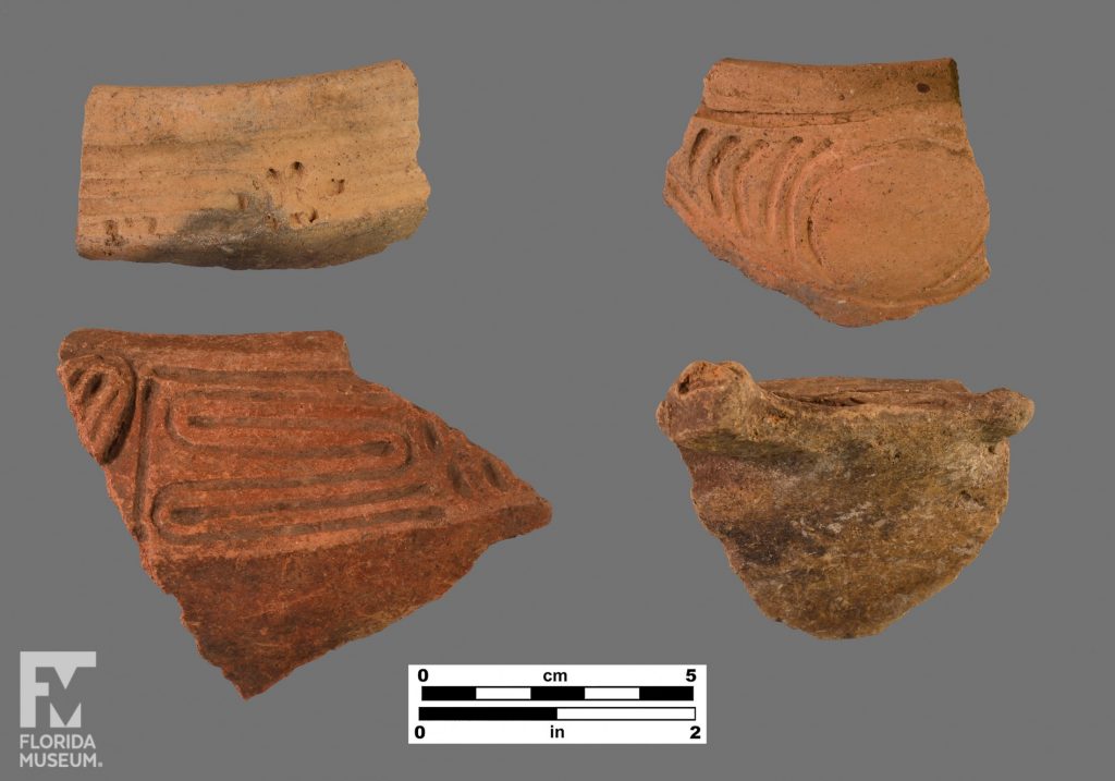 Formal artifact photo of four incised rim sherds, the bottom two also have small appliqué. One sherd has circular incisions while two have snaking-line incisions