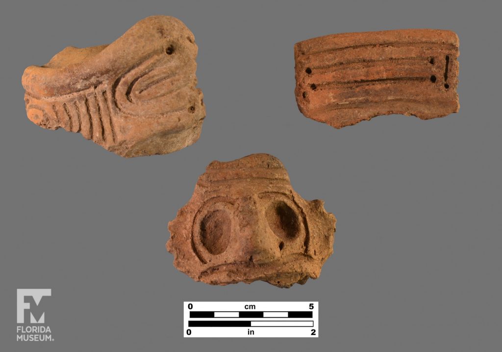 Three Chicoid sherds, the top left is a light colored sherd with circular incisions, the top right is a dark colored sherd with horizontal incisions. The bottom sherd is a face adorno with large eyes.