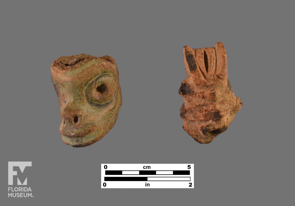Formal artifact photo of two Chicoid adornos, the left is a green face and the one on the right has a headdress.