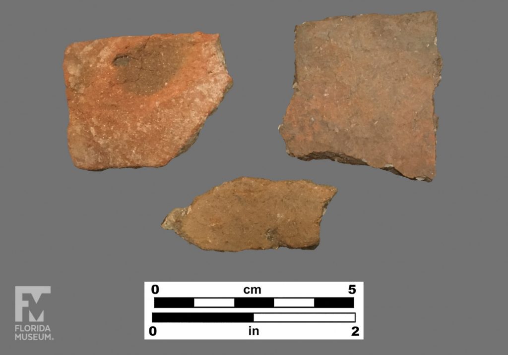 Formal artifact photo of three sherds, all red in color.