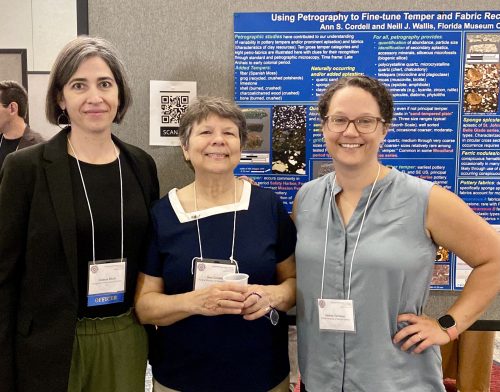 three women standing together in front of a research poster