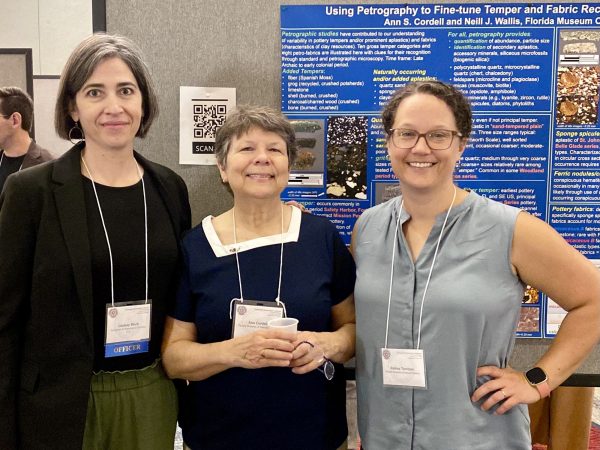 three women standing together in front of a research poster
