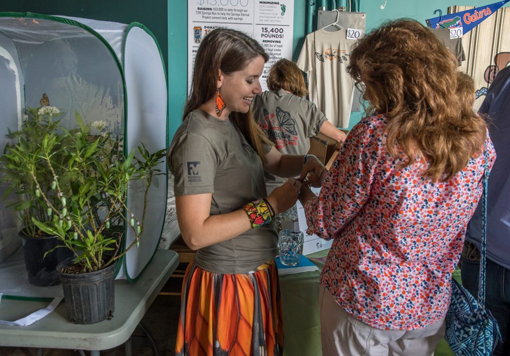 McGuire Center staff member shows a guest life butterflies displayed at the event