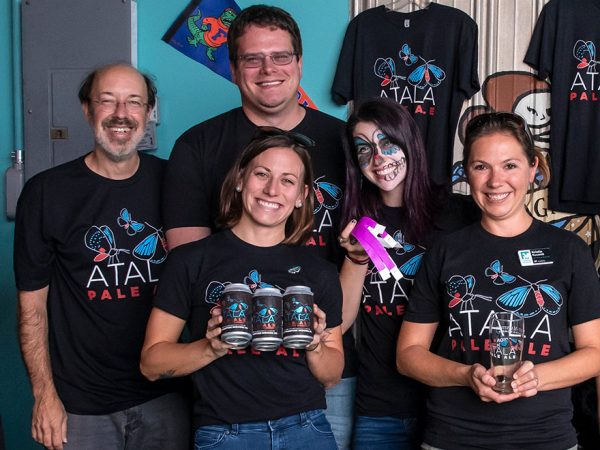 group of people wearing matching t-shirts standing at a merch table