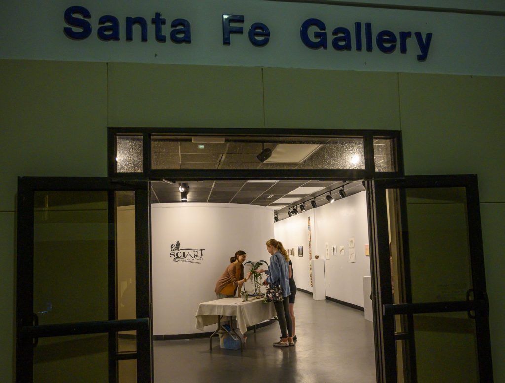 people standing at a reception table inside the doorway of an art gallery