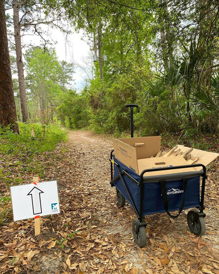 an arrow sign and a cart full of signs on a wooded path