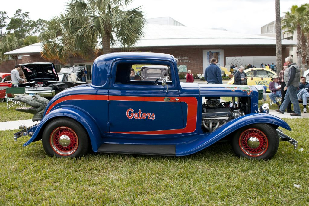 An antique car painted orange and blue with "Gators" painted on the side.