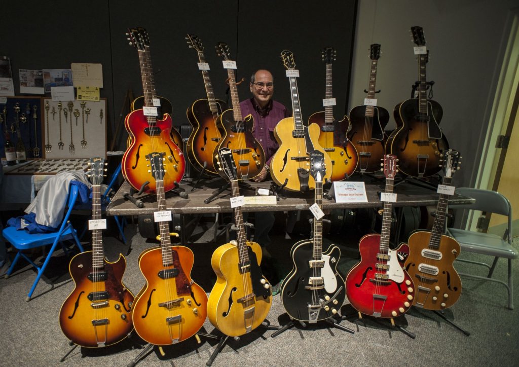 A man pictured with his guitar collection.