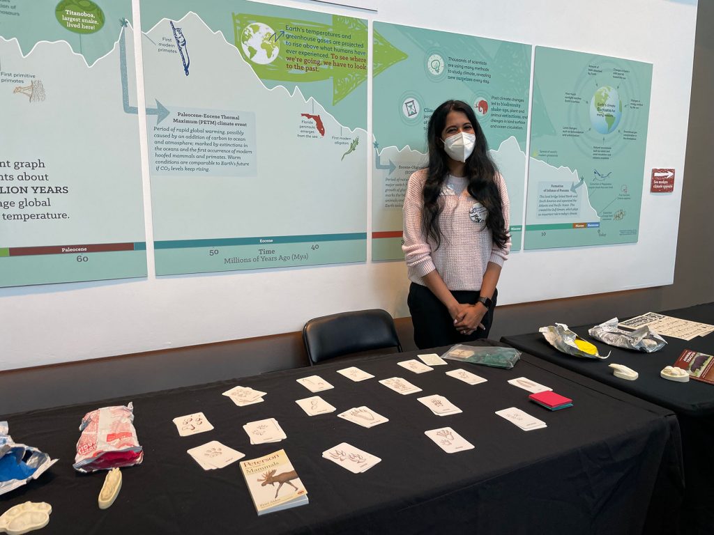 scientist wearing a mask stands behind table with display item during the women and girls in science celebration