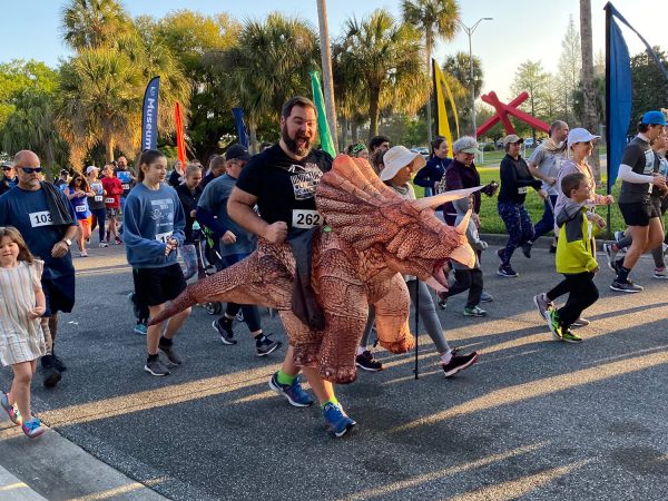 runners in the 5K, one runner is dressed up in a dinosaur costume