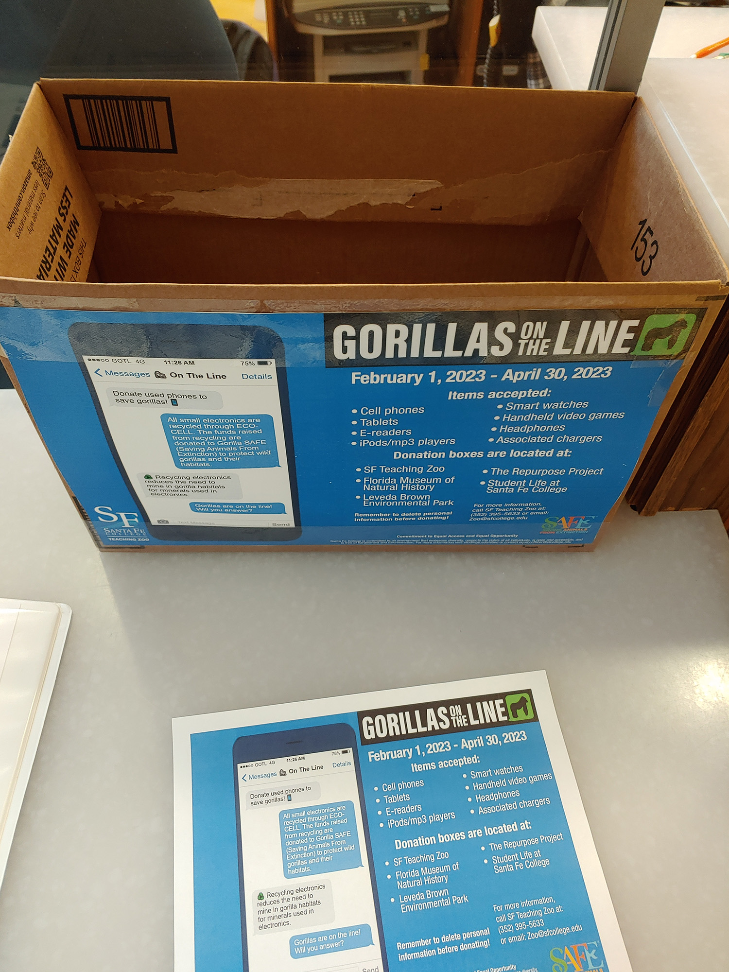the box in the Florida Museum lobby with a Gorillas on the line poster on the side of the box and on the table in front of the box