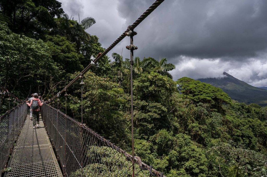 Arenal volcano in the distance of a scenic photograph taken from a suspension bridge in Costa Rica.