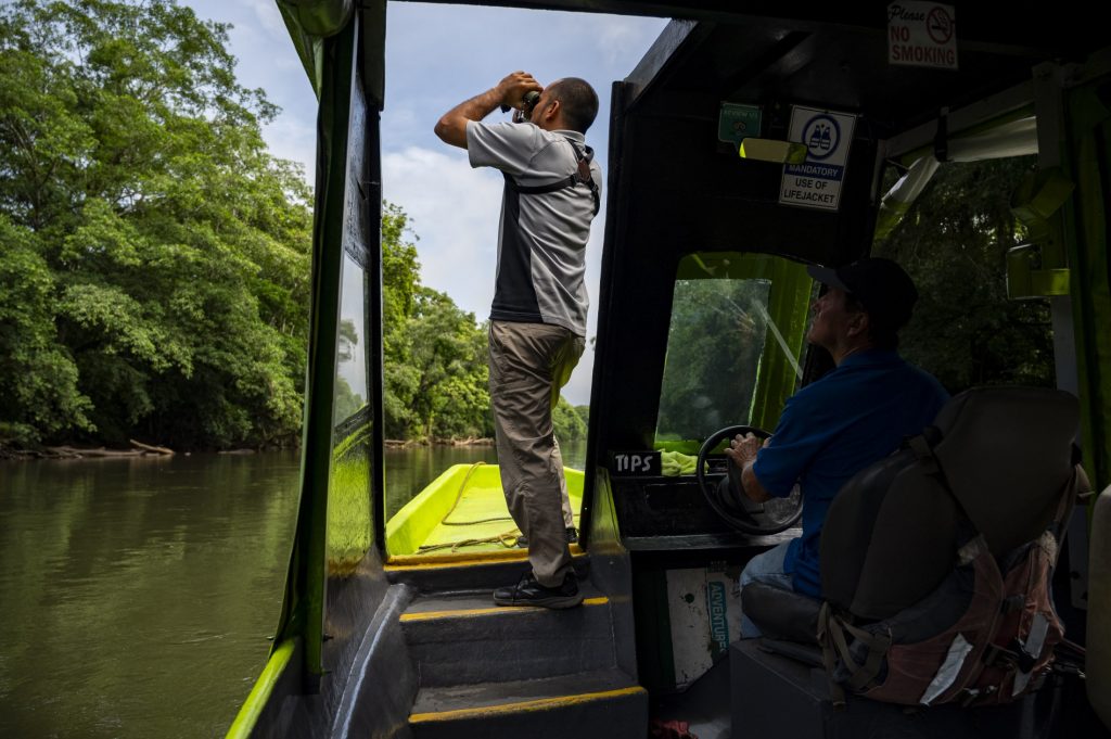 A person looks through binoculars from a boat on the Sarapiqui River in Costa Rica.
